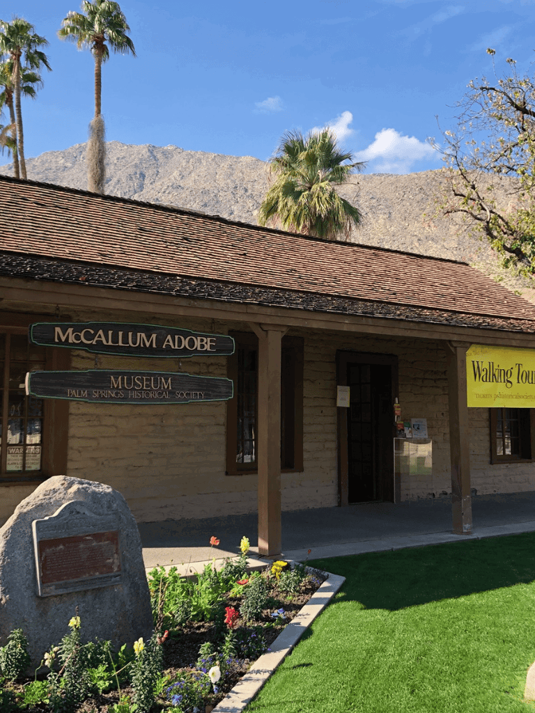 Historic museum building with palm trees and mountain backdrop in Palm Springs.