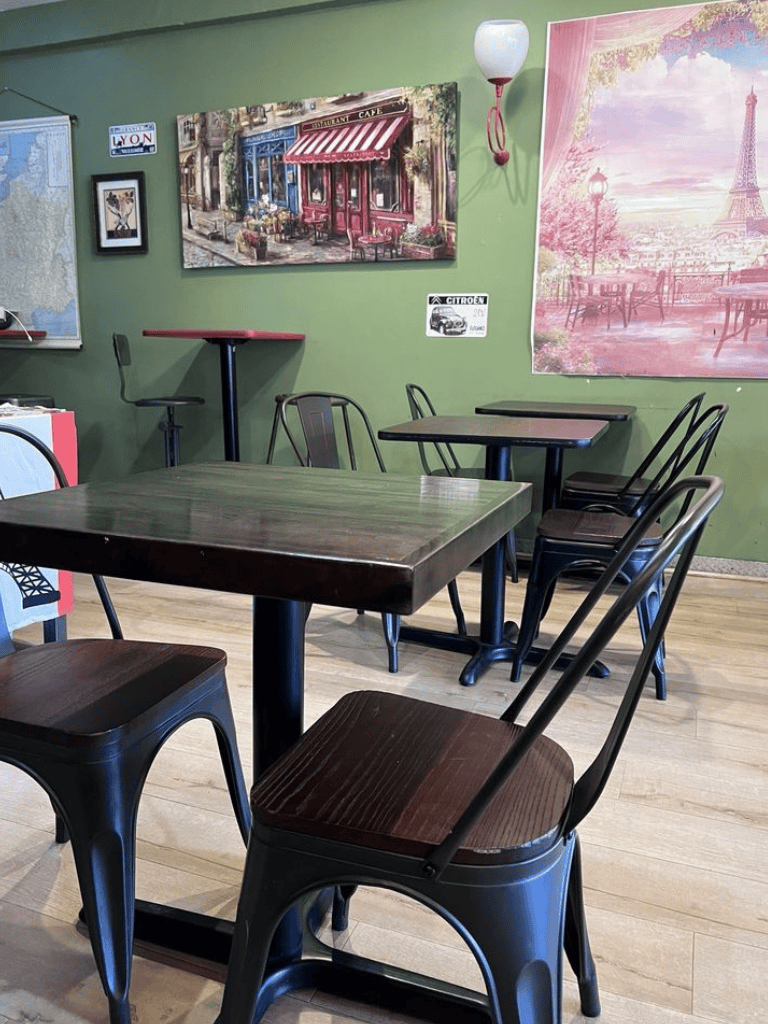 Cozy cafe interior with artwork of Paris and Parisian street scenes, ideal for relaxing breaks and casual dining.