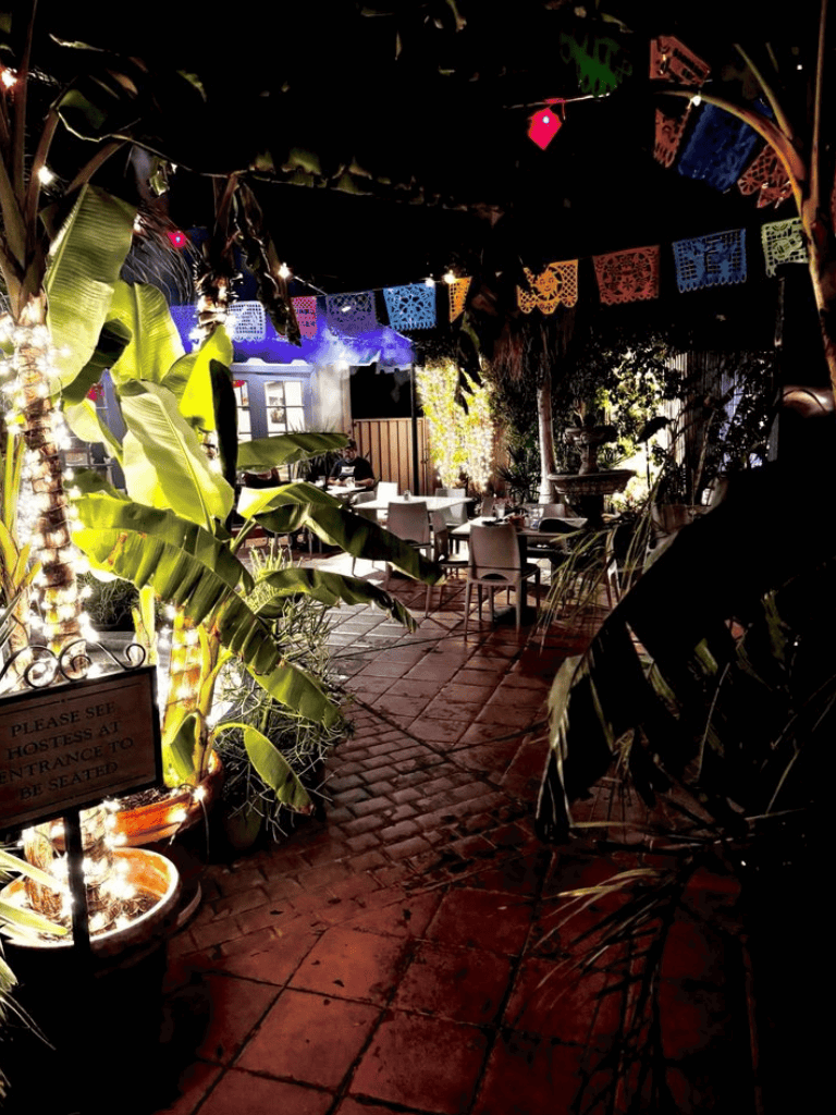 Lush outdoor restaurant with vibrant decorations and cozy seating area.