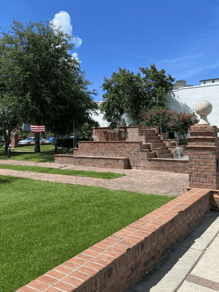 Aesthetic brick fountain with lush greenery, perfect for outdoor relaxation in historic downtown.