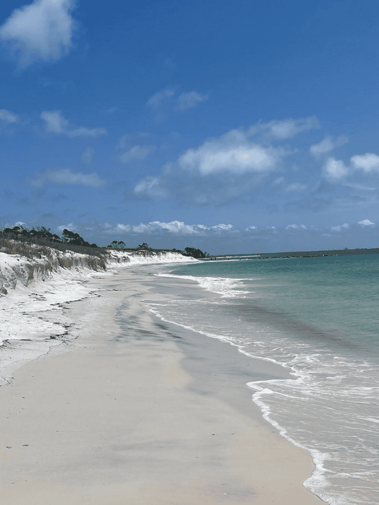 Serene beach with white sand, turquoise water, and blue sky, perfect for vacation and relaxation.