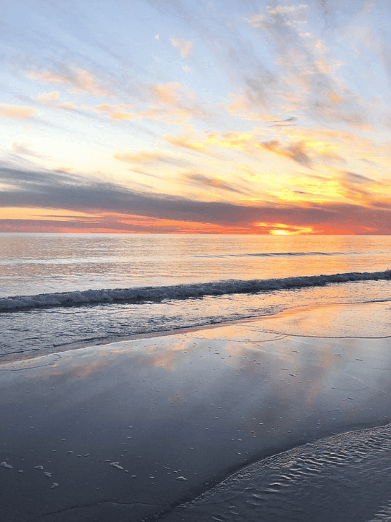 Tranquil beach sunset with colorful sky and gentle waves, perfect for relaxation and seaside escapes.
