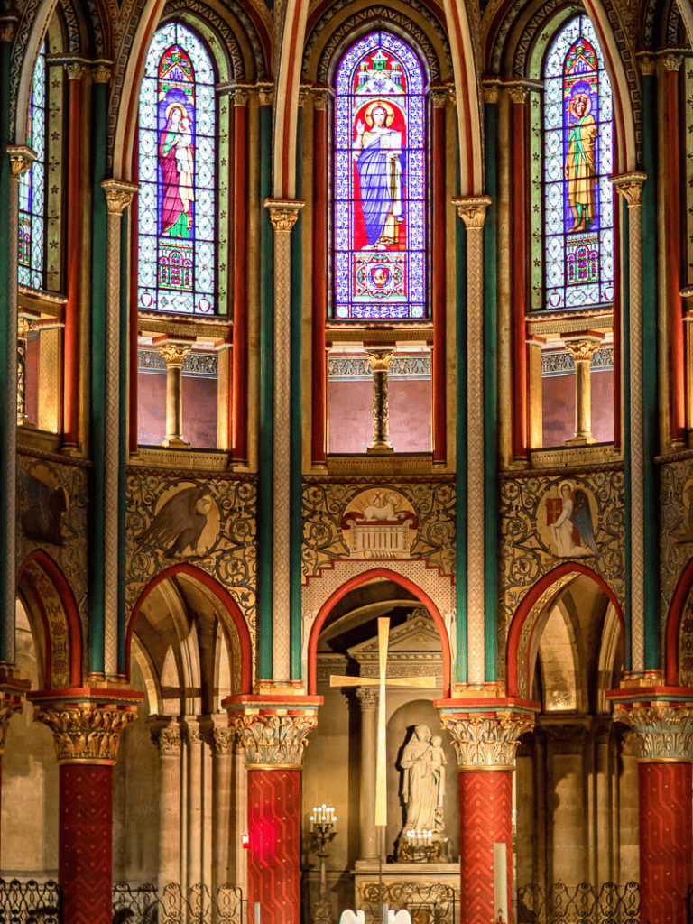Colorful stained glass church interior with religious statues and ornate architecture.