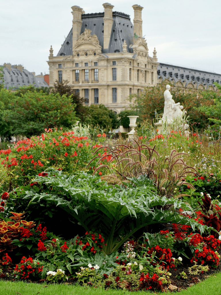 Lush flower garden with historic building backdrop in Paris, France.
