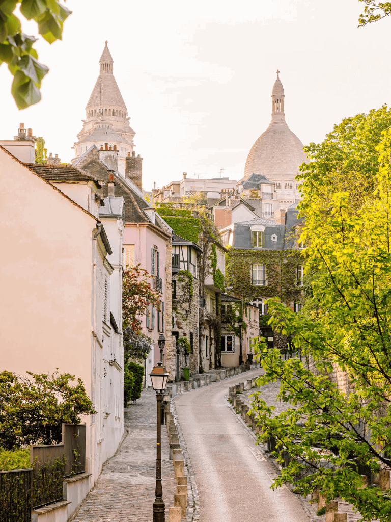 Charming Parisian street with historic architecture and iconic Sacré-Cœur Basilica in the background.