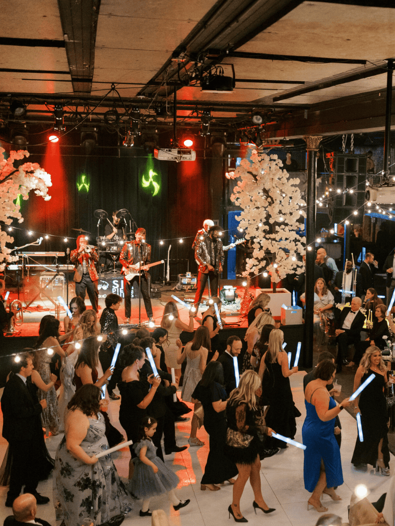 Elegant party with live band and dancing guests, festive lights, and floral decor at QuestForDirections event venue.