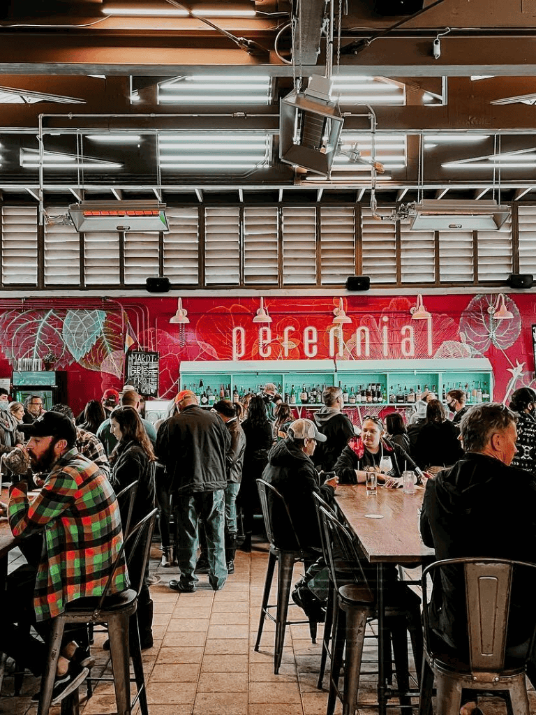 Bright, bustling vegan restaurant with vibrant wall art, social ambiance, and diverse crowd.