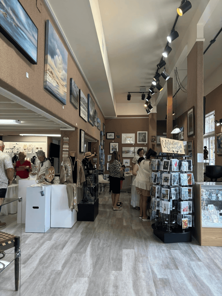 Art gallery interior showcasing paintings, framed photos, and art merchandise for sale.