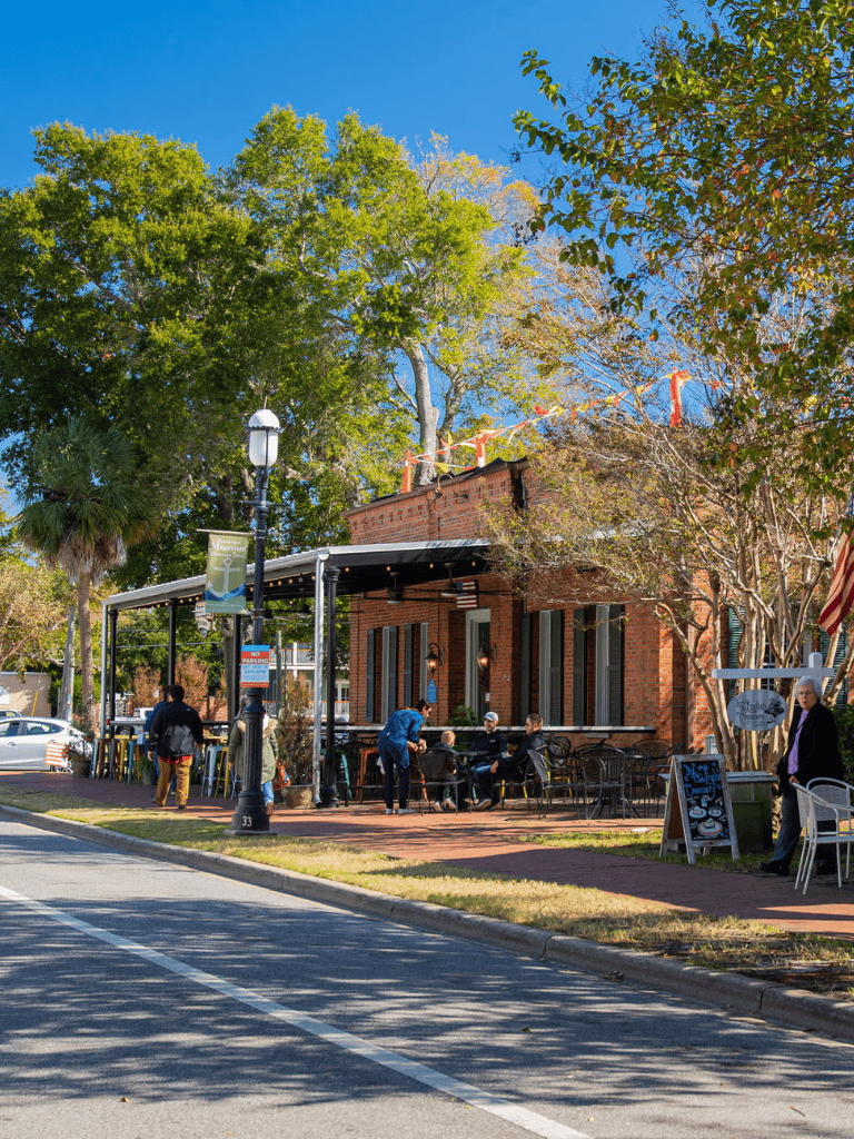 Outdoor cafe in a charming small town with brick buildings and lush trees.