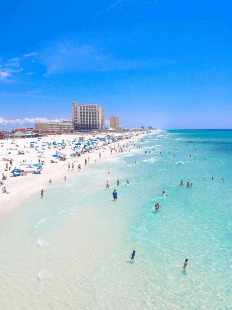 Bright sunny day at Panama City Beach, Florida with clear turquoise waters and bustling beach scene.