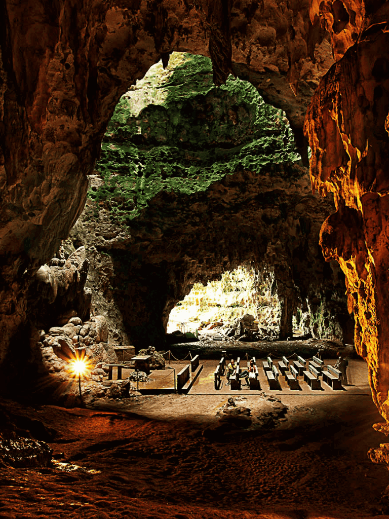 Deep cave with ancient ruins and green moss, natural lighting illuminating the mysterious interior.