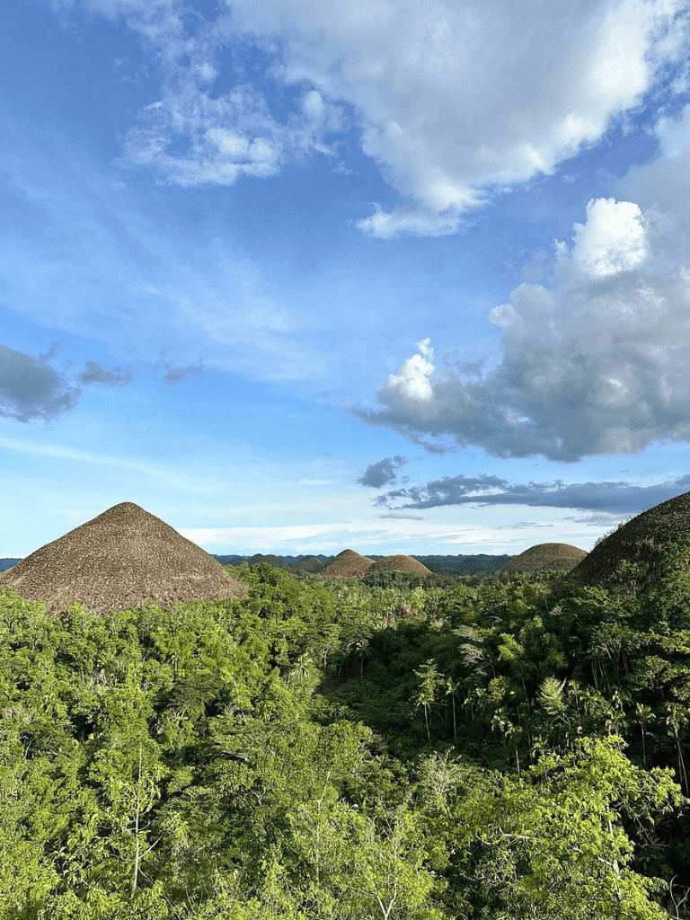 Ancient Mayan pyramids surrounded by lush green jungle under a blue sky with clouds.