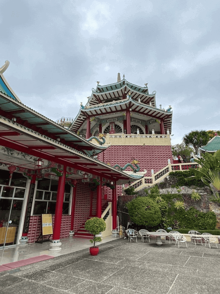Colorful Chinese pagoda with red brick walls and lush greenery, located at Quest For Directions.