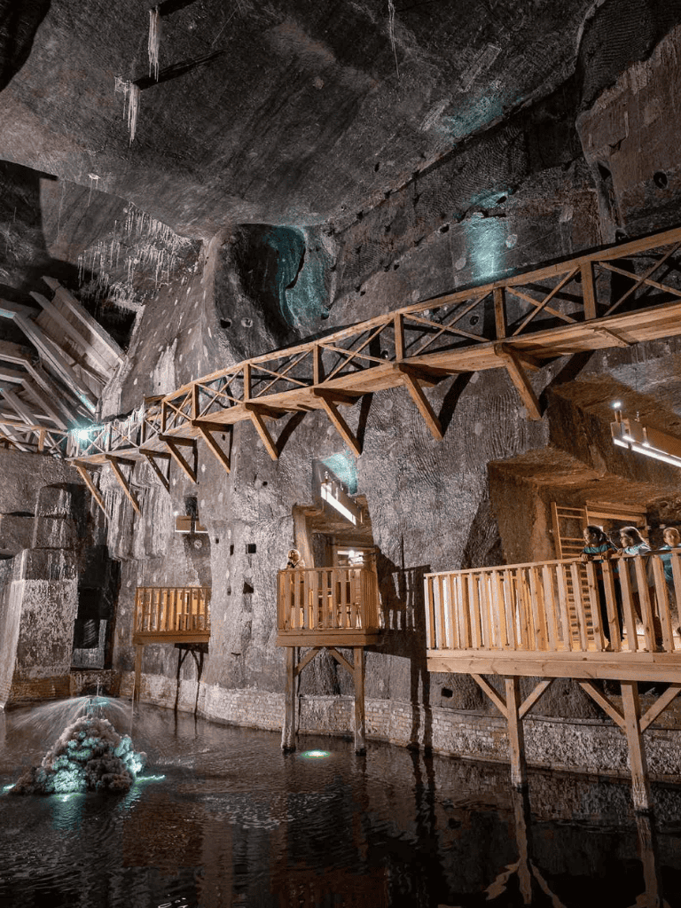 Ancient underground cave with wooden walkways, waterfall, and natural rock formations.