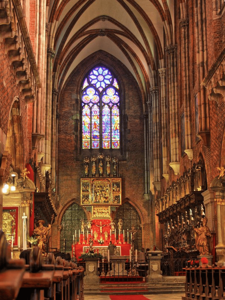 Intricate stained glass window in historic church interior with religious altar and ornate decorations.