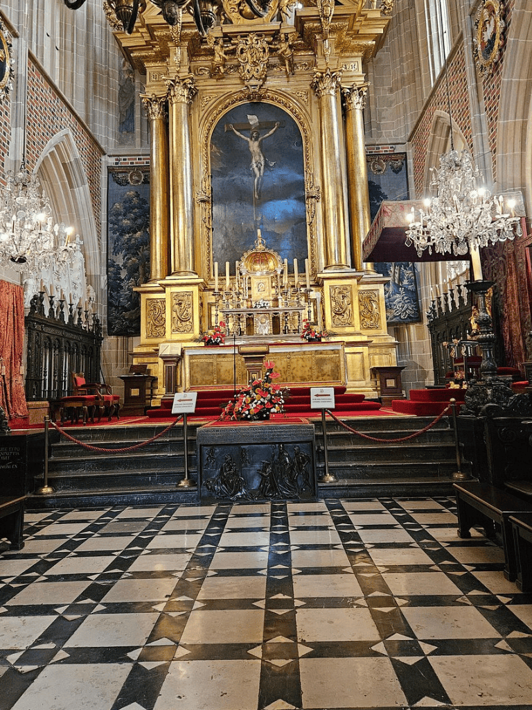 Intricate church altar with gold accents and religious artwork, showcasing historic sacred architecture.