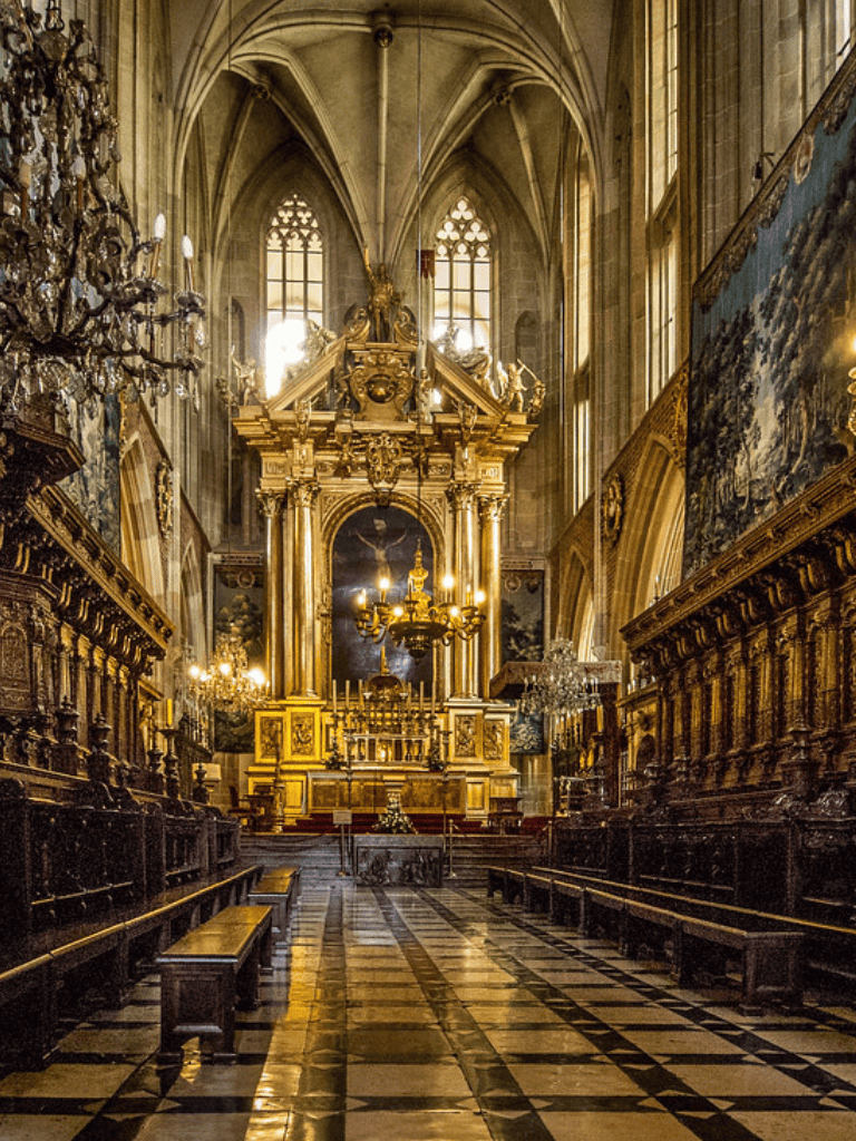 Opulent baroque church interior with gold gilded altar and chandeliers.