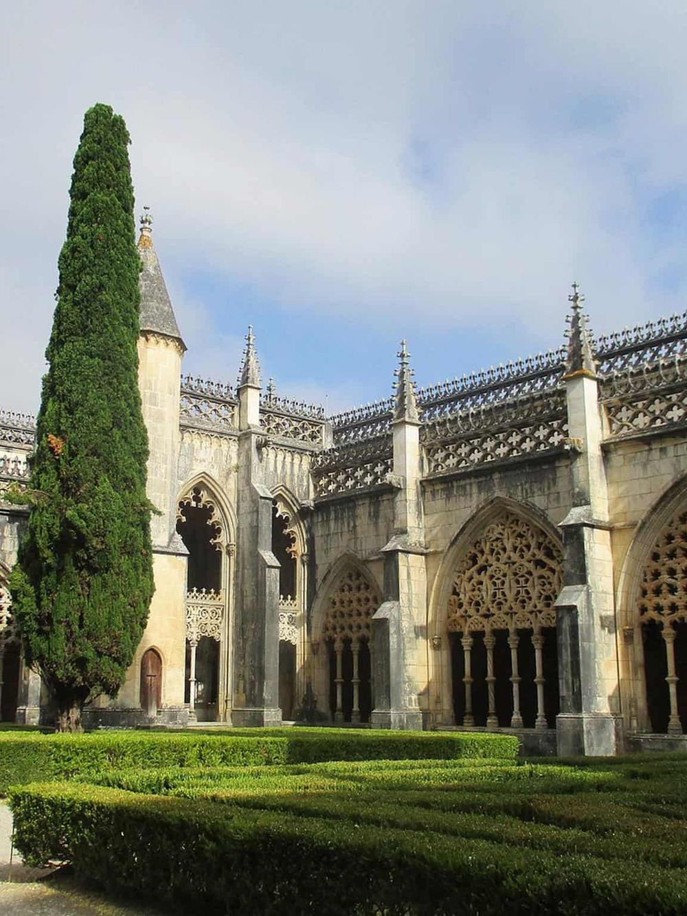 Majestic Gothic cathedral with intricate stonework and lush greenery, showcasing historic architecture and serene surroundings.