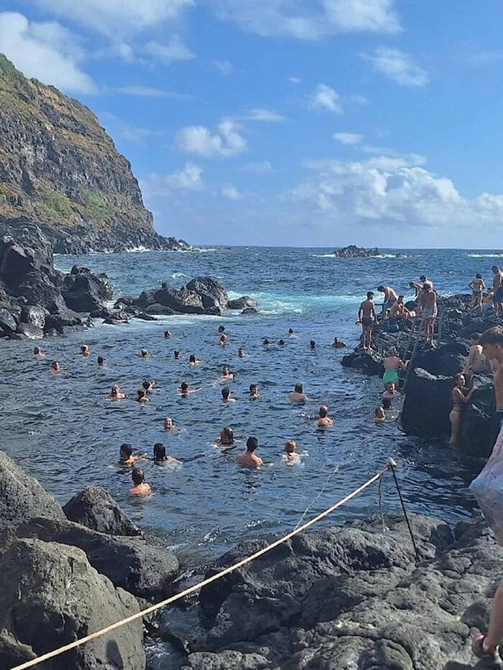 Swimming and exploring natural rock pools at a coastal destination with scenic cliffs and blue ocean.