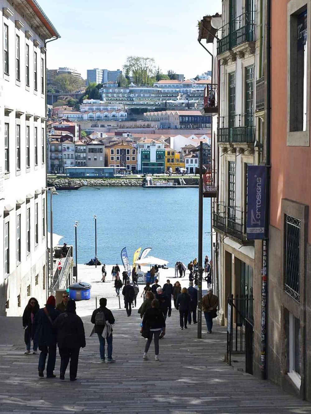 Colorful coastal cityscape with crowded steps leading to waterfront, vibrant buildings, and Hilly landscape, popular travel destination.