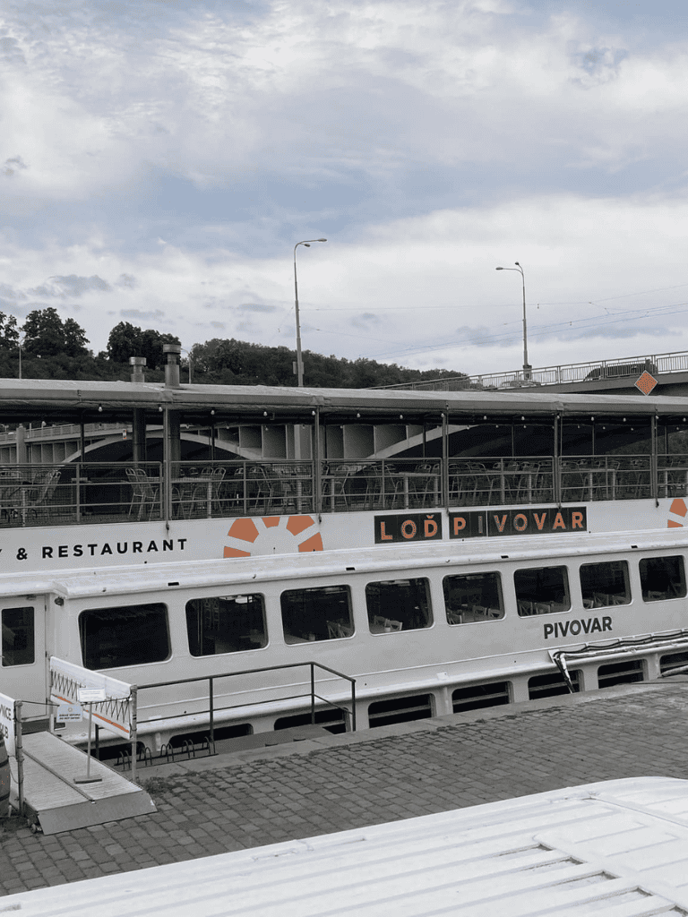Boat dock on a river with a restaurant sign, scenic background, and cloudy sky.