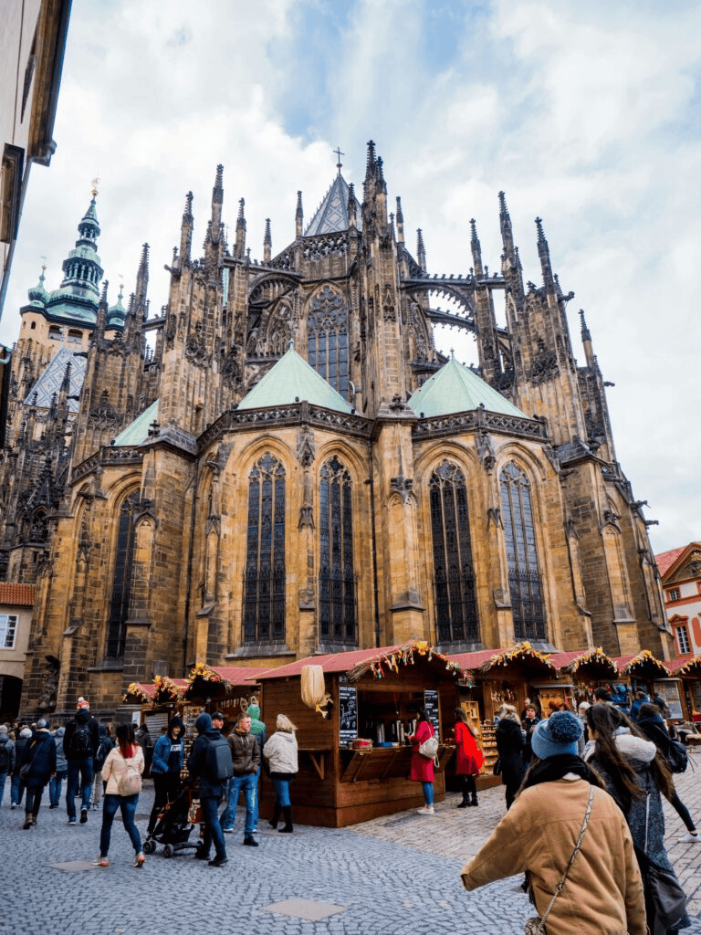 Ancient Gothic cathedral with holiday market stalls in a busy European city square.