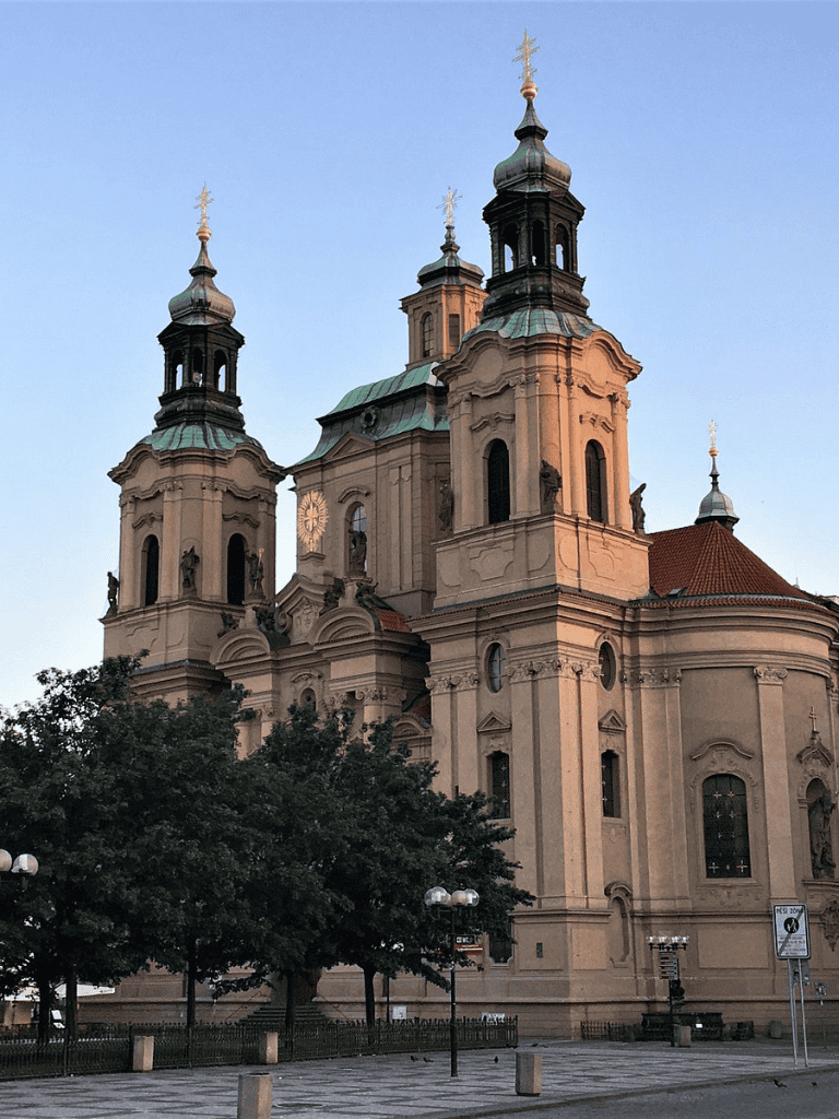 Historic Baroque church with ornate architecture and multiple towers in a city square.
