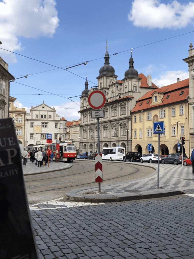 Historic European city street with tram, architecture, and street signage.