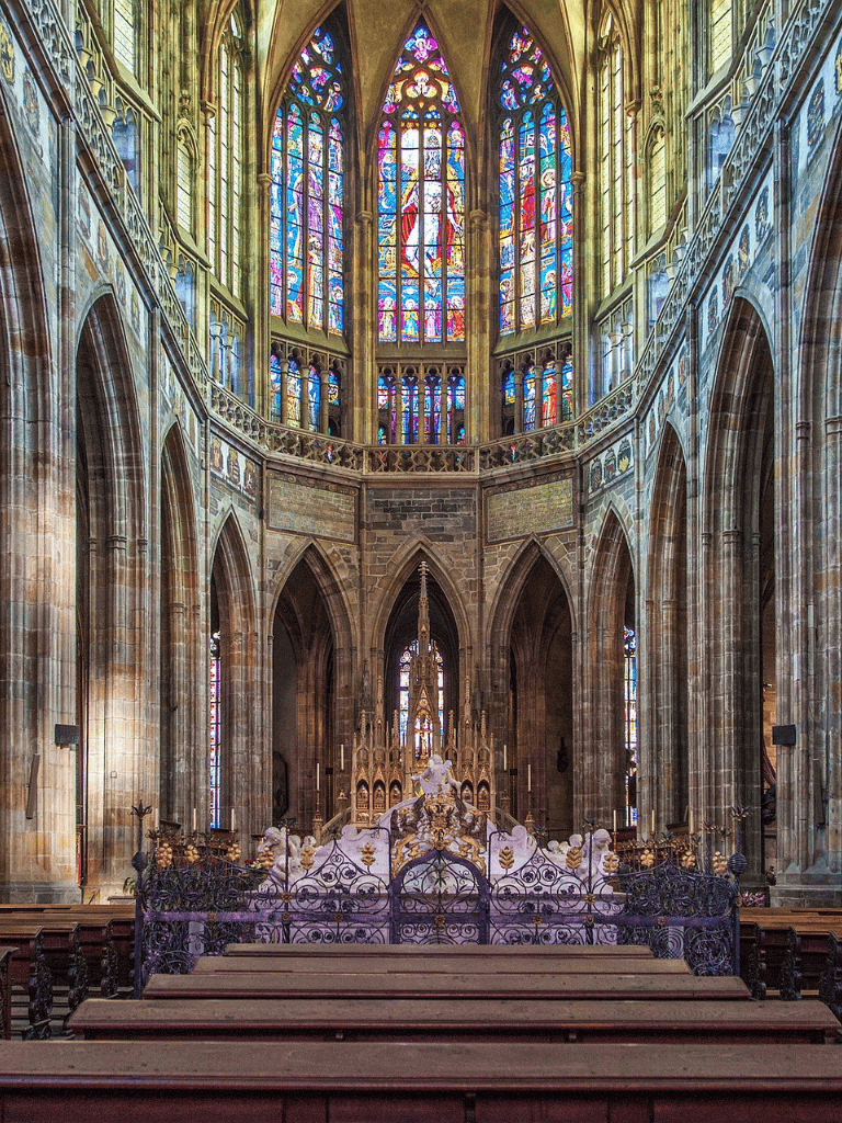 Ornate Gothic cathedral interior with stained glass windows and altar, showcasing religious architecture and artistic details.