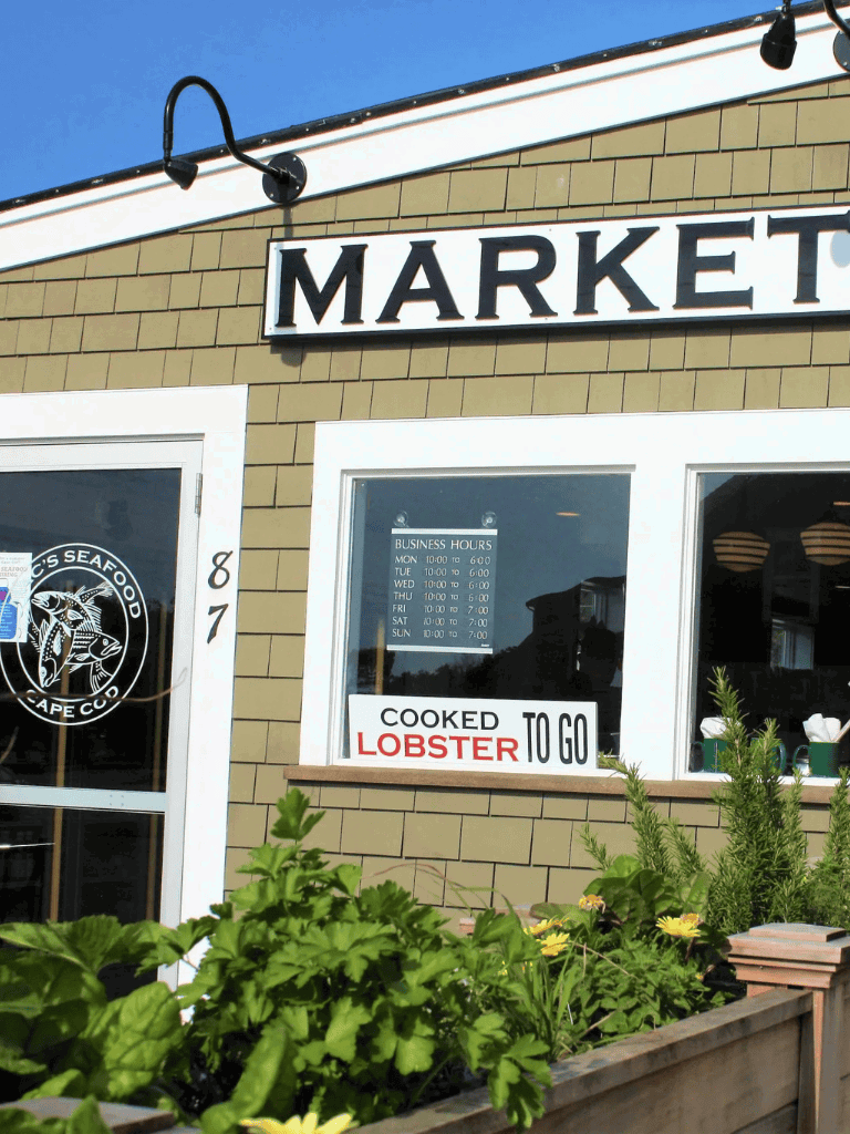 Market seafood restaurant exterior with business hours and cooked lobster sign.
