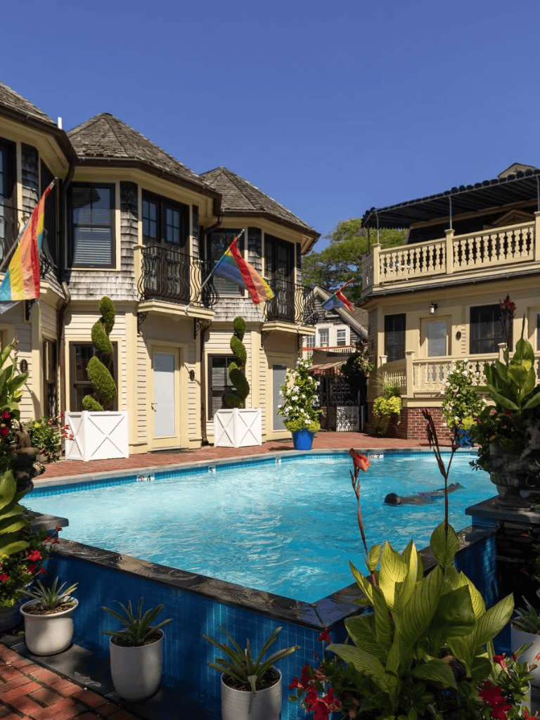 Luxurious hotel with pool, balconies, upscale decor, lush plants, and colorful flags.