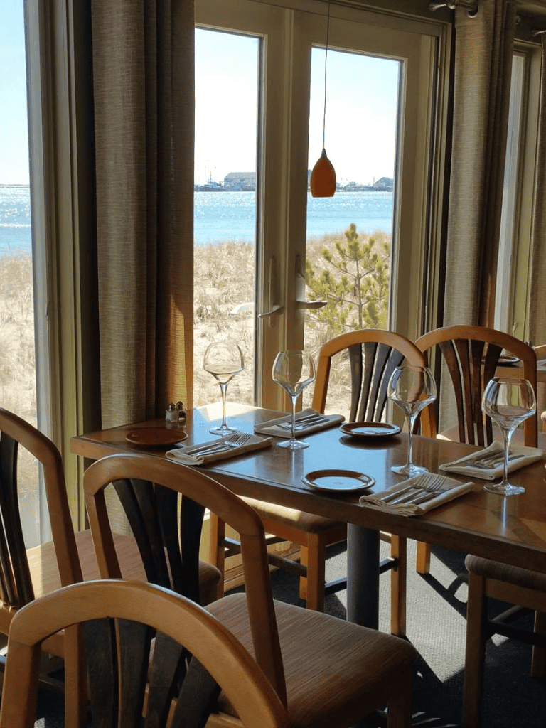 Cozy lakeside dining room with large windows, elegantly set table, and scenic water views.