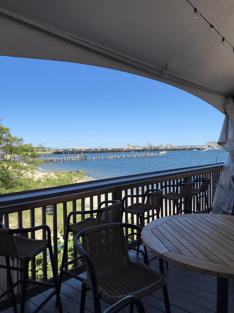 Breathtaking water view from a seaside restaurant balcony, featuring outdoor dining and scenic harbor scenery.