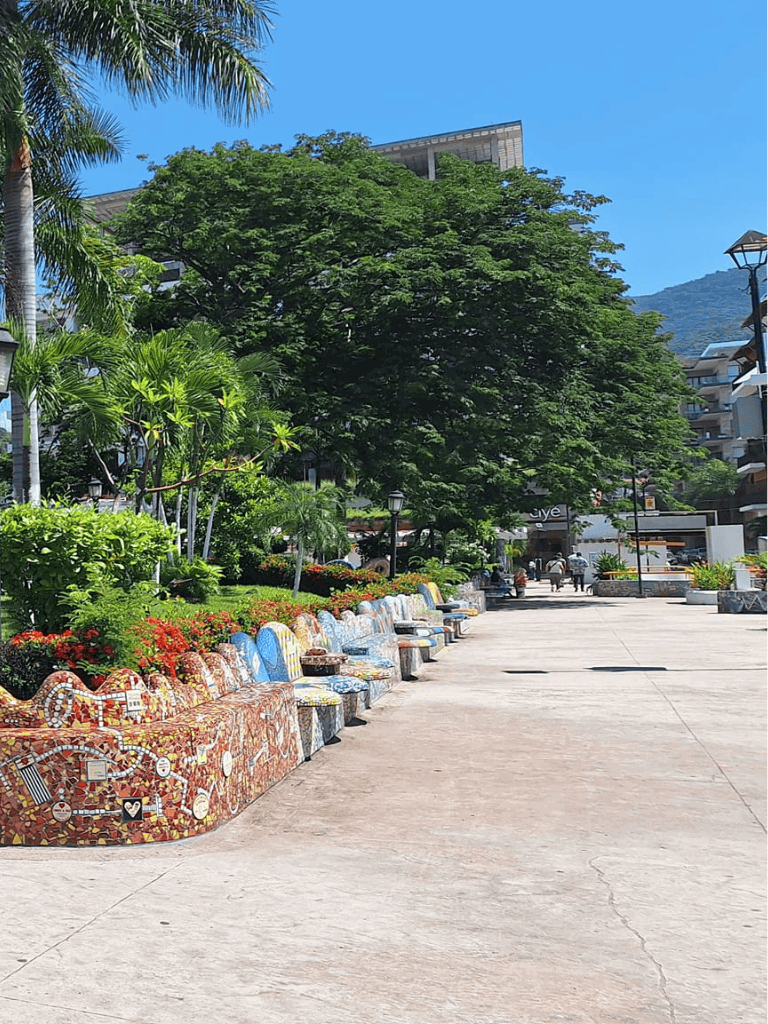 Colorful mosaic benches in a lush outdoor park with tropical trees and mountain views.
