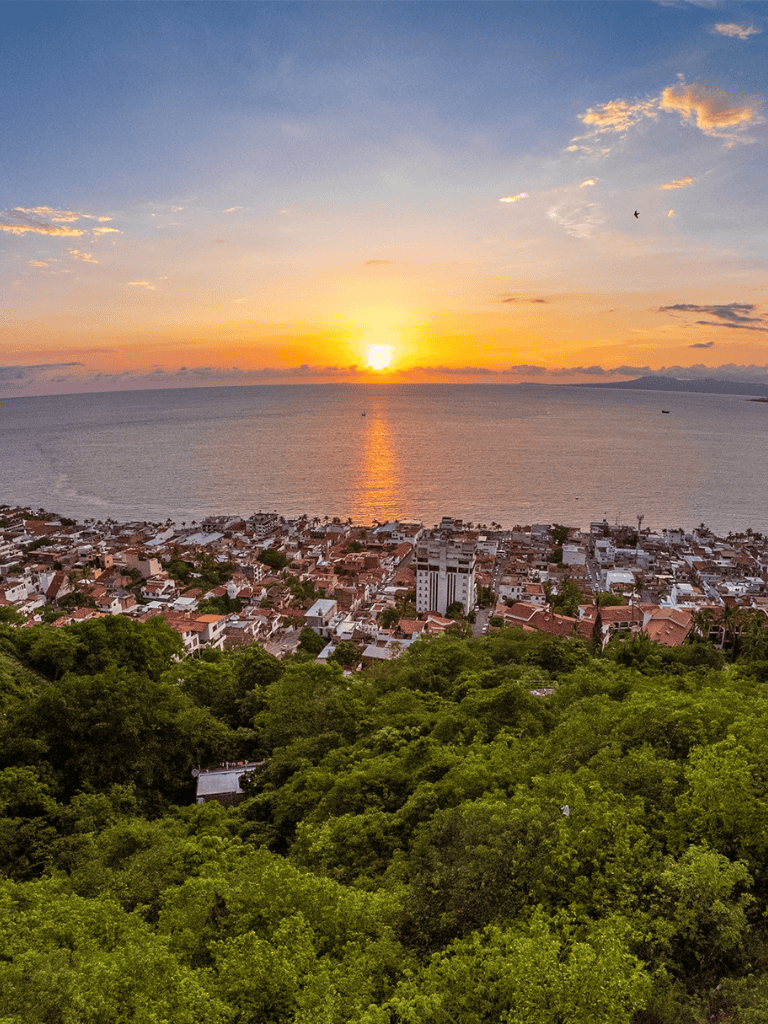 Sunset view over coastal town with lush greenery and ocean horizon, perfect for travel and adventure seekers.