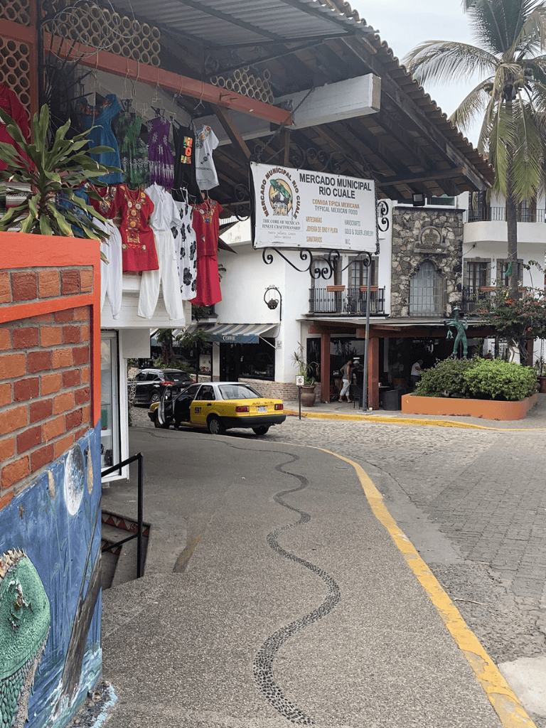 Colorful Mexican market with clothing stalls and classic taxi in Rio Cuale, Puerto Vallarta.