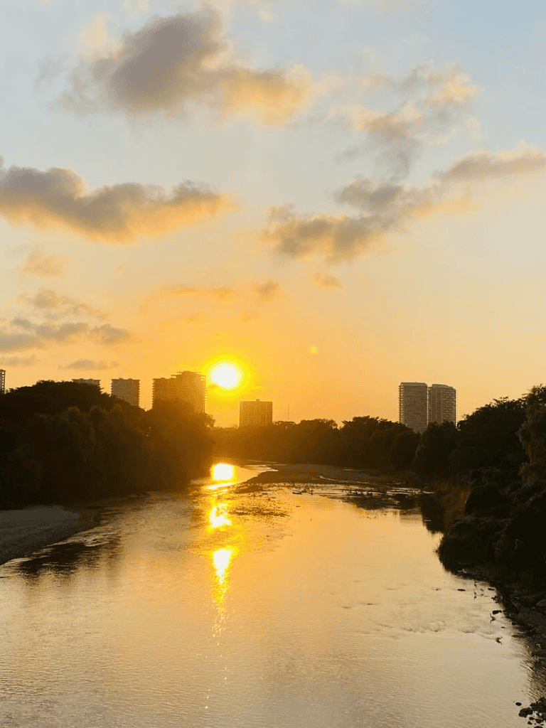 Sunset over river with city skyline in background, peaceful urban scenery, beautiful evening landscape.