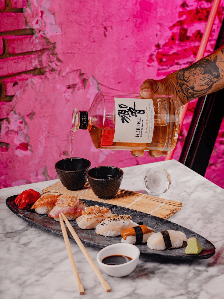 1. Sushi and whiskey on marble table with pink background.