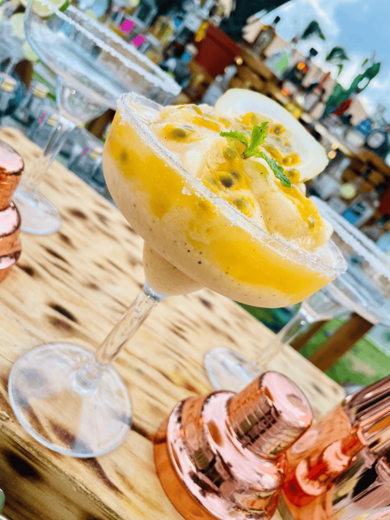 Fresh passion fruit margarita in a cocktail glass with salted rim at an outdoor bar.