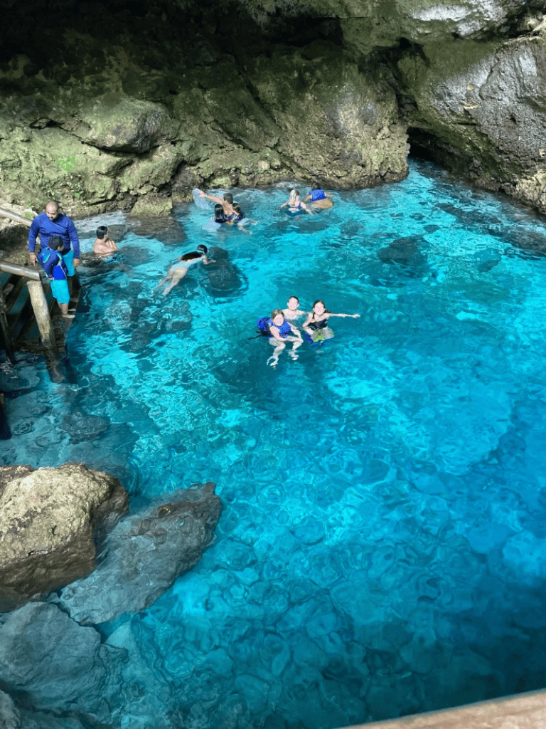 Refreshing blue canyon pool in a natural cave with visitors swimming and exploring.