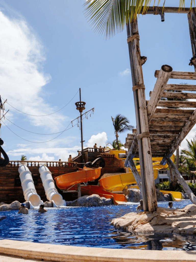 Bright tropical water park with colorful slides and a pirate ship theme for family fun.