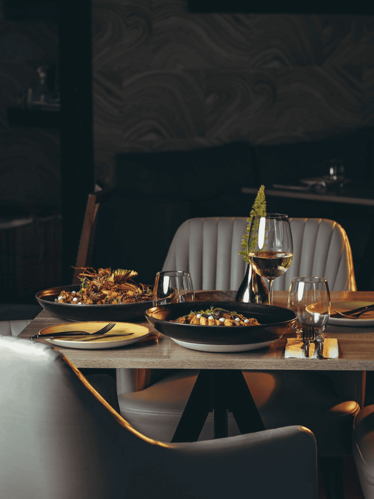 Elegant restaurant table setting with wine glasses and gourmet dishes for fine dining experience.