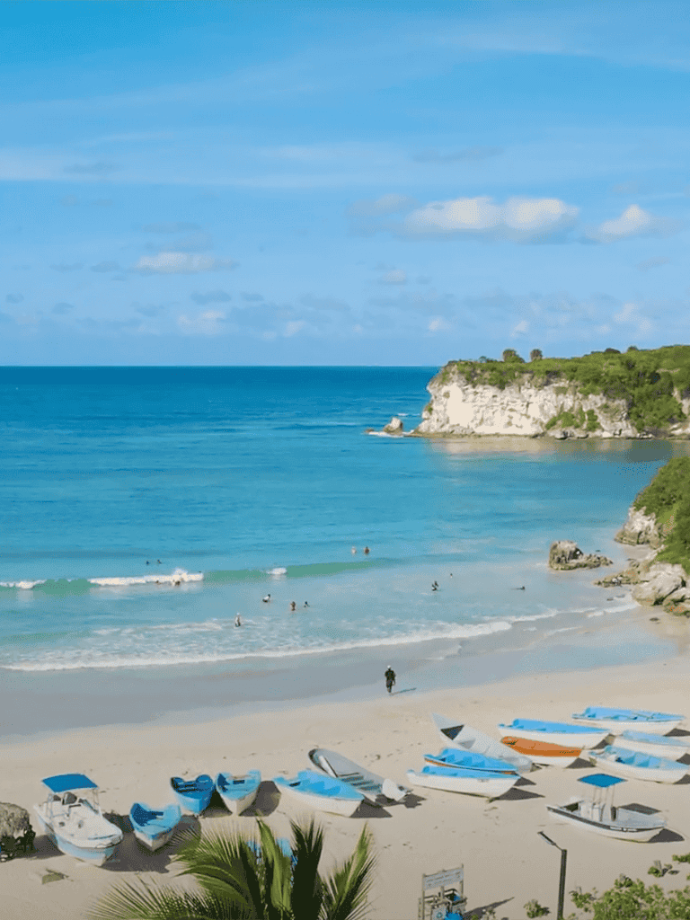 Relaxing coastal beach with boats and cliffs, perfect for vacation planning and travel guidance.