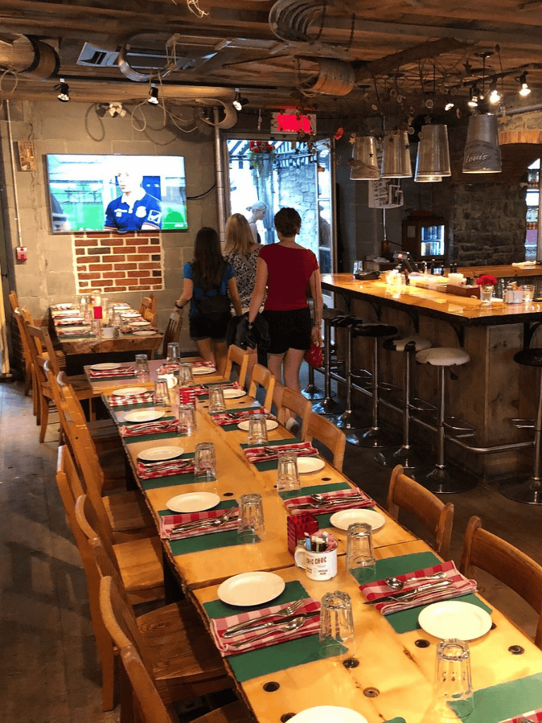 Cozy restaurant with wooden tables, colorful place settings, and a TV, perfect for family dining and sports viewing.