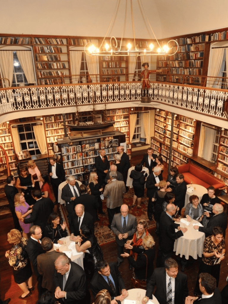 Library book collection event with sophisticated guests, elegant atmosphere, and vintage decor.