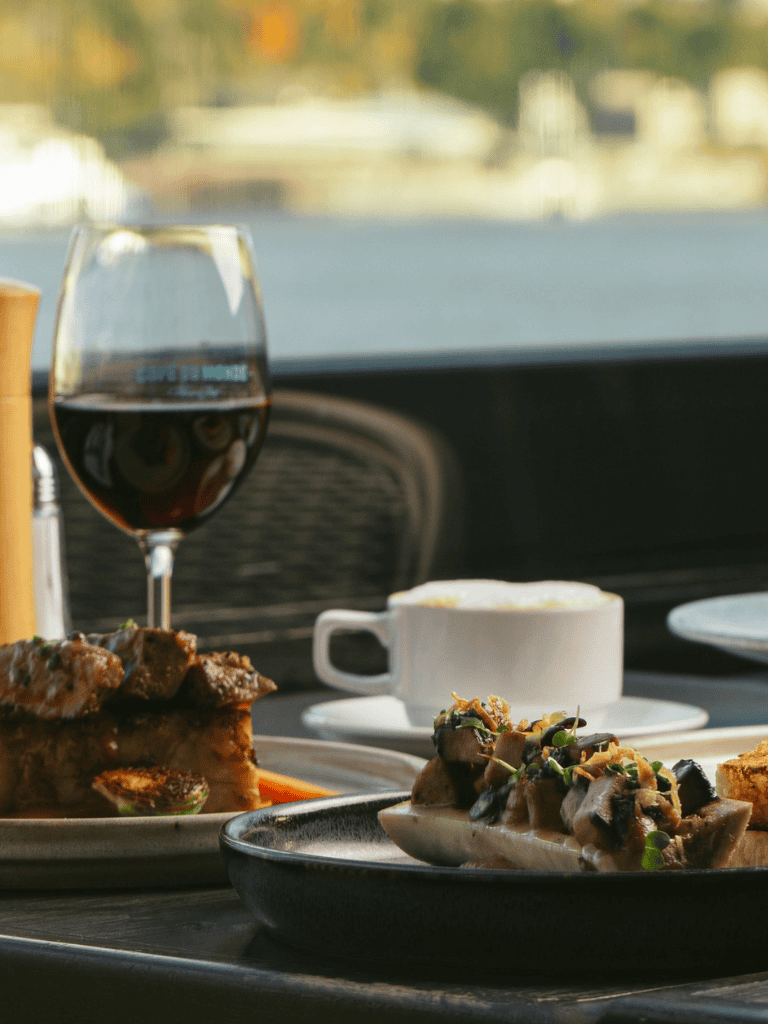 1. Wine glass, coffee cup, and gourmet dishes in car, promoting travel dining experiences.