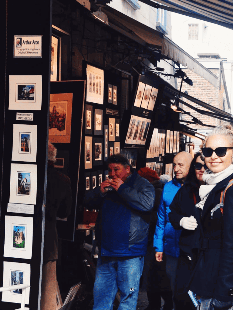 Art gallery street scene with framed artwork display and visitors browsing.