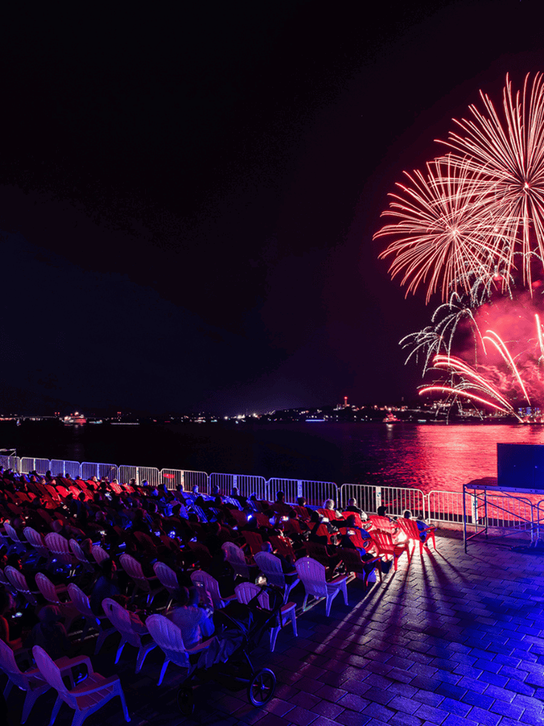 Spectacular fireworks display over water with outdoor audience enjoying night show at QuestForDirections event.