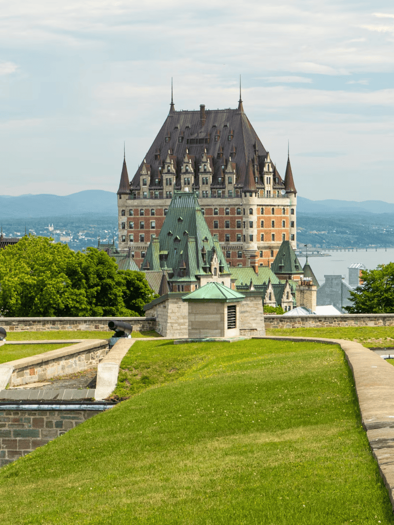 Fairy tale castle in Quebec with lush green landscape and scenic river view.