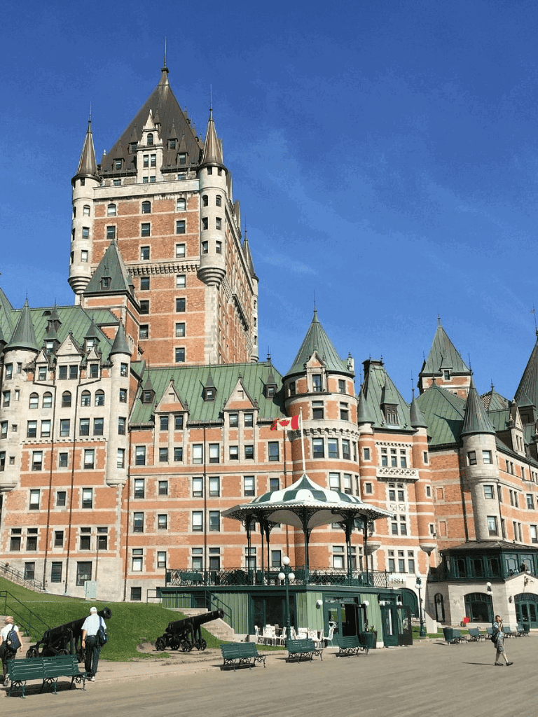 Vintage castle-style hotel with green rooftops and cannons in front, located in Canada.